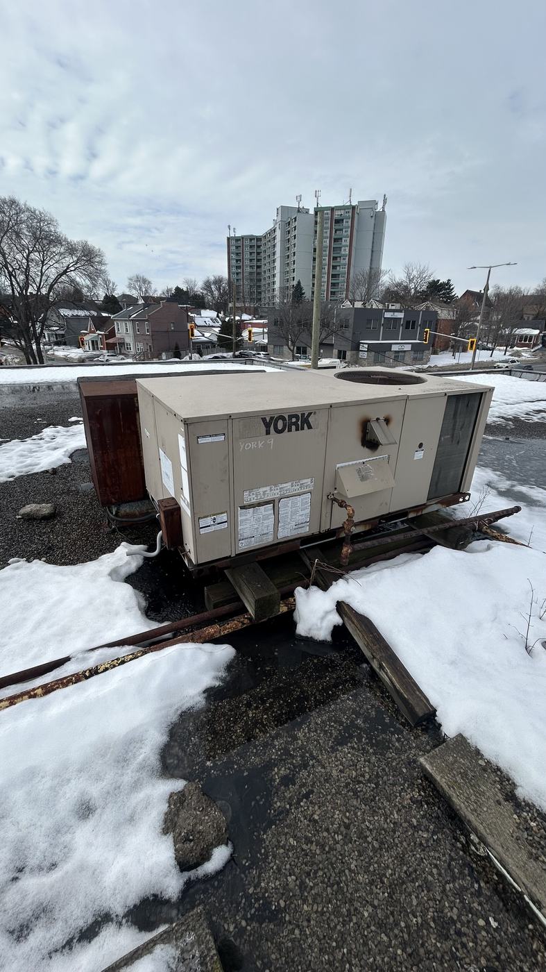 Rooftop packaged unit sitting on a corroded curb on a commercial roof